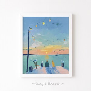 May include: A framed art print featuring a painted scene of two figures sitting on a wooden pier at sunset. The sky is a gradient of blue, orange, and yellow, with string lights hanging above. Seagulls are present on the pier and in the sky.