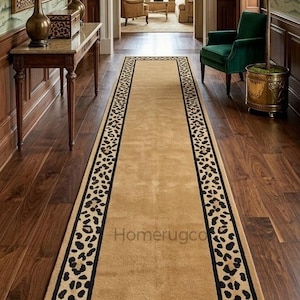 May include: A rectangular beige runner rug with a black and tan leopard print border. The rug is centered in a hallway with dark wood flooring and walls. The text "Homerugco" is visible on the rug.