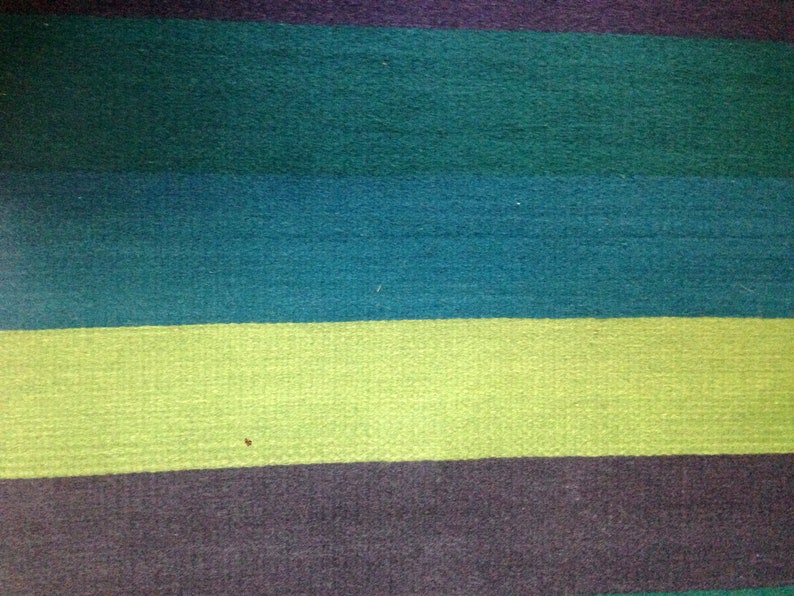 May include: A close-up of a striped fabric with alternating bands of dark teal, light teal, light green, and dark gray.