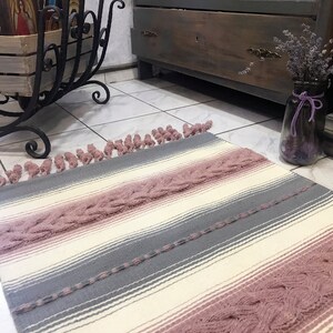 Unique handwoven woolen rug with cable knitted plates and crocheted fringies. Pink, gray and white floor rug. Art home textile.