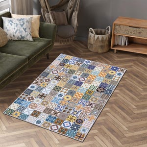 Puede incluir: Una alfombra rectangular con un diseño de patchwork multicolor compuesto por numerosas baldosas cuadradas pequeñas. Cada baldosa muestra un patrón geométrico o floral único en tonos azul, amarillo, marrón, blanco y verde, creando un efecto mosaico.