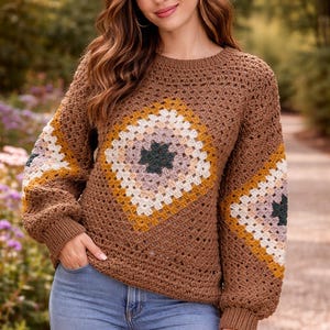 May include: A brown crochet sweater with a geometric design on the front and sleeves. The design features squares of yellow, white, pink, and green. The sweater has a crew neck and long sleeves.