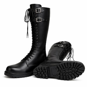 May include: Black knee-high boots with a lace-up design and two buckle straps. The boots have a thick, textured sole and are made of a smooth, leather-like material. The boots are approximately 40 cm tall.