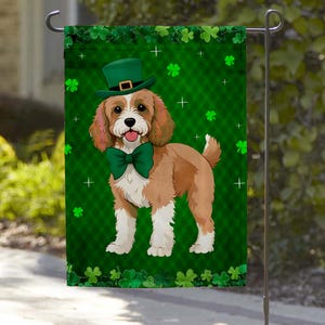 May include: A St. Patrick's Day garden flag featuring a Cavalier King Charles Spaniel wearing a green top hat and bow tie. The dog is brown and white, set against a green background with shamrocks and crosses.