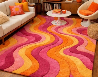 May include: A vibrant, retro-style area rug with a wavy pattern in shades of pink, orange, and yellow. The rug's design evokes a 1970s aesthetic, adding a pop of color and a bold statement to any living space. The rug is made of a soft, plush material.