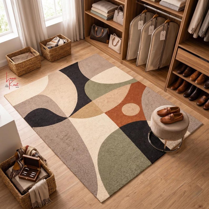 May include: A rectangular area rug featuring a geometric pattern of overlapping circles and arcs in shades of cream, charcoal, sage green, tan, and terracotta. The rug is placed on a light wood floor in a room with a wooden closet and woven baskets.