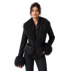 May include: A black jacket with a faux fur collar and cuffs. The jacket has a suede-like texture and a tailored fit. The faux fur is a dark, curly style, adding a luxurious touch. The model is wearing black jeans.