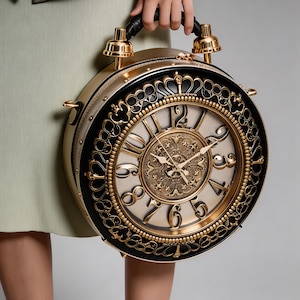 May include: A distinctive, circular handbag styled as a vintage clock. It has a gold-coloured frame, black detailing, and a cream-coloured clock face with gold numerals and hands. The handle is black leather.