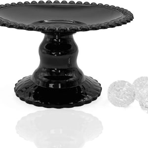 May include: A black, ornate cake stand with a scalloped edge and a decorative base. Three clear, faceted glass spheres are next to the stand. The stand is made of a glossy material and reflects light.