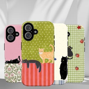 May include: Four phone cases with cat designs. The cases feature pink, green, and white backgrounds with floral, polka dot, and gingham patterns. Each case has a different cat illustration, including black and orange tabby cats.