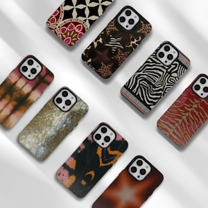 Könnte beinhalten: Eine Sammlung von Handyhüllen mit verschiedenen Mustern. Designs umfassen Batik, Zebrastreifen, Tiermuster und florale Motive. Die Hüllen sind in Braun-, Rot-, Schwarz- und Weißtönen gehalten und bieten eine Reihe von Stilen.