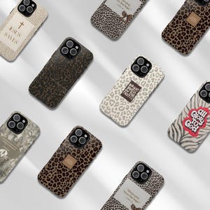 May include: A collection of phone cases with various designs. Some cases feature leopard print, while others display religious text and symbols, including a cross and phrases like "Jesus Saves" and "All Glory to God." The cases have a glossy finish.