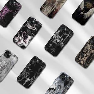 May include: A collection of nine smartphone cases featuring dark, intricate graphic designs. The cases display various motifs including abstract floral patterns, celestial imagery, gothic crosses, and skull illustrations in black, white, and muted tones.