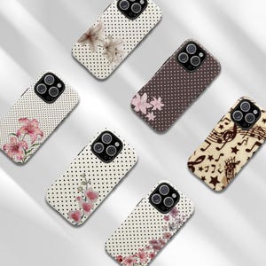May include: A collection of phone cases with various designs. Some cases feature a white background with black polka dots and floral patterns in pink and white. Other cases have brown polka dots or musical notes.