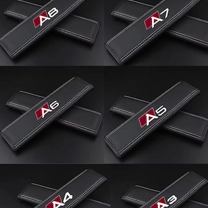 以下が含まれることがあります： 白いステッチと赤と白のロゴが入った黒いシートベルトショルダーパッド。パッドにはA8、A7、A6、A5、A4、A3とラベルが貼られています。パッドは滑らかな素材で作られています。