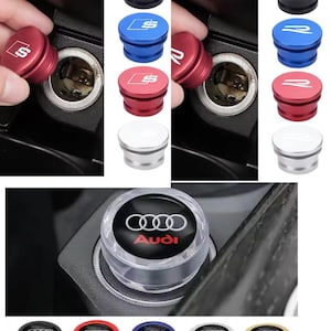 May include: A collection of car cigarette lighter port covers in various colors, including black, blue, red, and silver. Each cover features a logo, with some displaying the Audi logo and others the "S" or "R" logo.