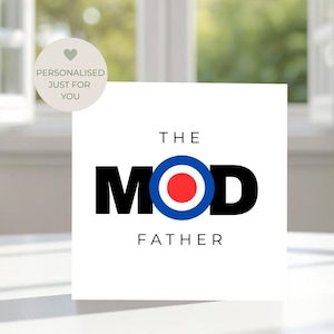 May include: A white square card with the words "THE MOD FATHER" in black text. The word "MOD" features a bullseye design in the center. A small circular sticker with the text "PERSONALISED JUST FOR YOU" is in the upper left corner.