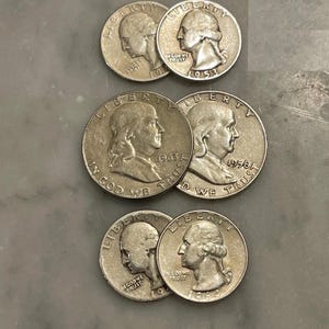 May include: A collection of silver United States quarters and half dollars. The coins display profiles of historical figures and the inscriptions "LIBERTY" and "IN GOD WE TRUST", with visible dates including 1953, 1958, 1964, and 1965.