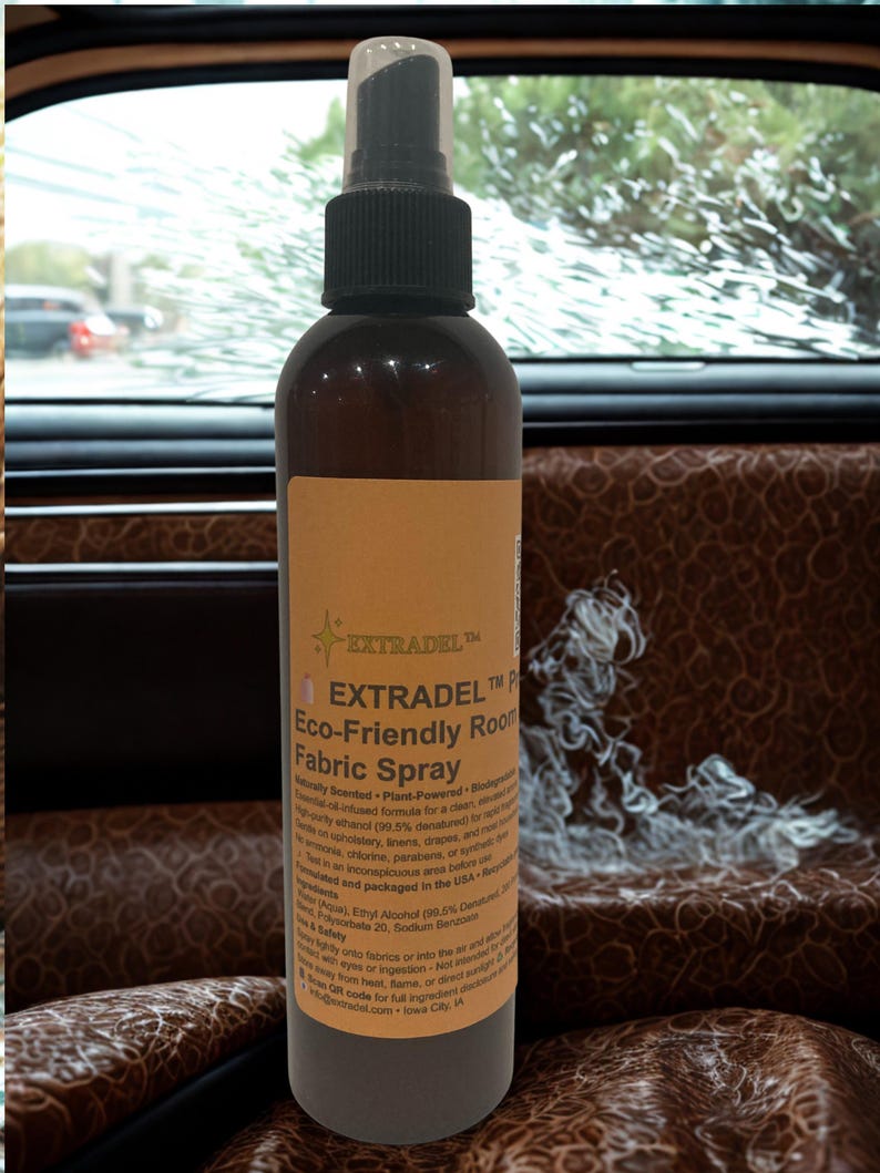 May include: A brown spray bottle with a black nozzle and a tan label. The label reads "EXTRADEL Eco-Friendly Room Fabric Spray". The bottle is in front of a car seat with a brown leather pattern.