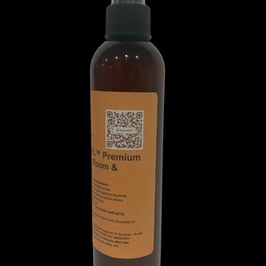 May include: A brown spray bottle with a black cap and a label. The label has text that reads "Premium Room &" and a QR code. The bottle contains a liquid and is designed for room fragrance dispersal.