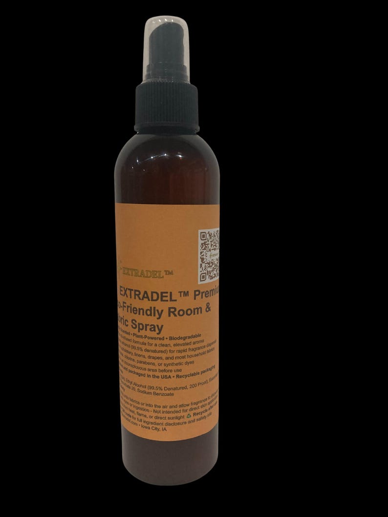 May include: A brown spray bottle with a black nozzle and a white cap. The label reads "EXTRADEL" and "Premium Fabric Spray". The bottle contains a liquid and is designed for use in rooms and on fabrics. The product is plant-powered and biodegradable.