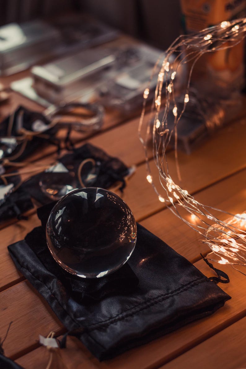 a clear glass sphere resting on a black cloth, with a string of lights visible in the background.