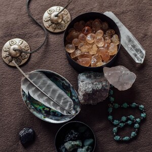 a collection of various crystals, gemstones, and jewelry arranged on a brown surface.