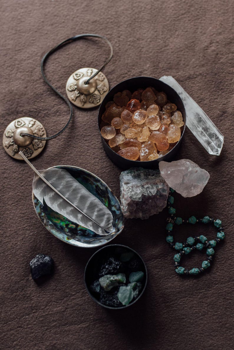 a collection of various crystals, gemstones, and jewelry arranged on a brown surface.
