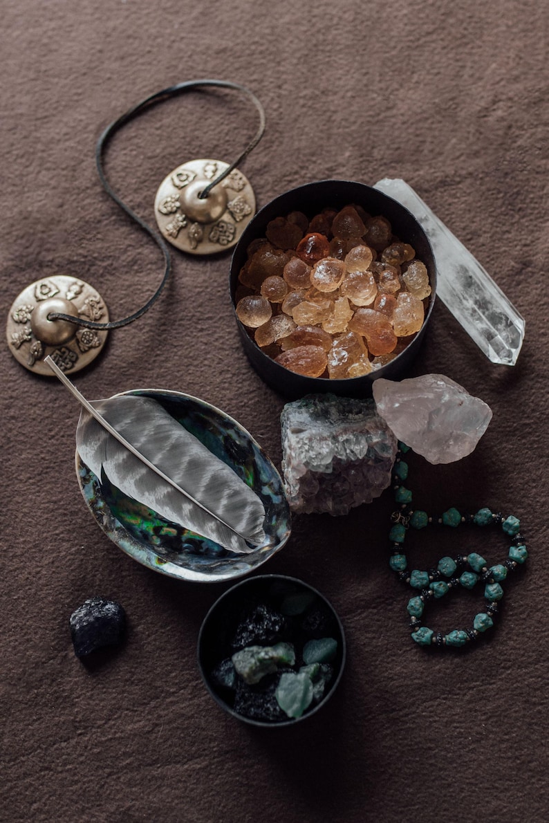 a collection of various crystals, gemstones, and jewelry arranged on a brown surface.