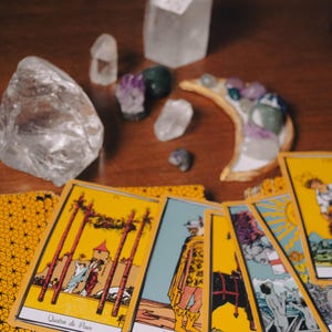 a collection of tarot cards and crystals arranged on a wooden surface.