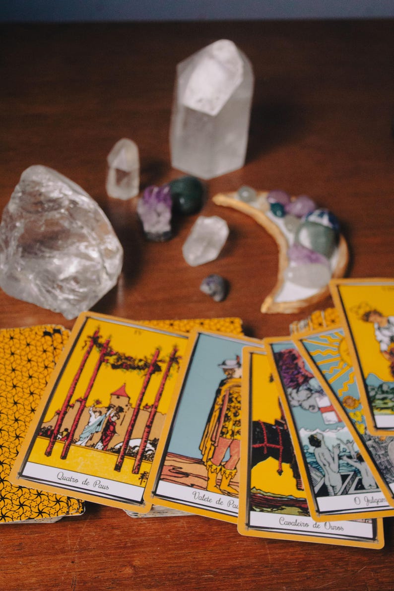 a collection of tarot cards and crystals arranged on a wooden surface.