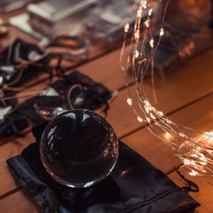 a clear glass sphere resting on a black cloth, with a string of lights visible in the background.