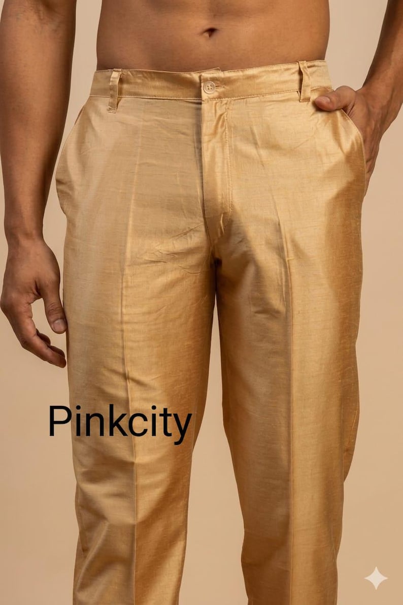 May include: Gold-colored trousers with a slight sheen, featuring a button closure and pockets. The text "Pinkcity" is printed at the bottom of the image. The pants appear to be made of a smooth, possibly silk-like fabric.