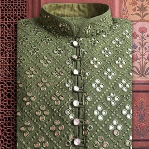 May include: An olive green embroidered kurta with mirror detailing and a mandarin collar. The kurta has a diamond pattern with small mirrors and large pearl-like buttons. The text "PINKCITY" is at the top.