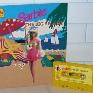 May include: A vintage Barbie "The Big Splash" cassette tape and book cover. The book cover features a Barbie doll in a pink skirt and a beach scene with sailboats. The cassette tape is yellow.