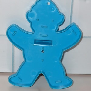 May include: A bright blue plastic gingerbread man cookie cutter. The cutter has a classic gingerbread man shape with arms outstretched and legs apart. It features a hole for hanging and is made of durable plastic.