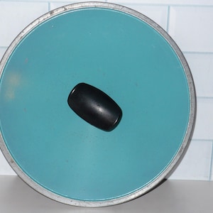 May include: A teal blue round lid with a black rubber knob on top.