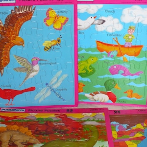 May include: Four Puzzle Patch 25-piece picture puzzles with pink borders. One features an eagle, butterfly, bee, hummingbird, cardinal, and dragonfly. Another shows a bird, fisherman in a boat, frog, fish, and ducks. Others depict dinosaurs and a map.