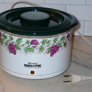 May include: A set of three ceramic mugs with a speckled, cream-colored glaze. Each mug features a different hand-painted design: a blue and green leaf, a yellow flower, and a red berry. The mugs have a simple, modern design.