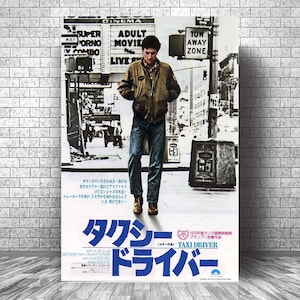 May include: A movie poster for "Taxi Driver" featuring a man in a jacket and jeans walking on a city street. The poster has Japanese text and the title "TAXI DRIVER" in large blue letters. The poster is displayed against a brick wall.