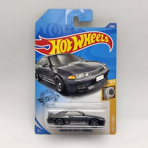 Könnte beinhalten: Hot Wheels Modellauto eines dunkelgrauen Nissan Skyline GT-R (BNR32). Das Spielzeugauto befindet sich auf einer blau-gelben Karte mit dem Hot Wheels-Logo und dem Text "HW Turbo". Das Modell ist 2/250 in der Serie.