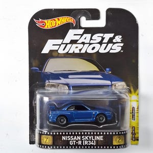 Puede incluir: Un coche de juguete Hot Wheels Nissan Skyline GT-R (R34) azul en su embalaje original. La tarjeta presenta el logotipo de Fast & Furious en la parte superior y un gráfico de tira de película en la parte inferior con el texto NISSAN SKYLINE GT-R (R34).