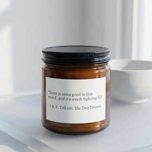 May include: A scented candle in a glass jar with a black lid. The candle has a white label with a quote from J.R.R. Tolkien: "There is some good in this world, and it's worth fighting for."
