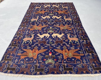 May include: A rectangular, hand-knotted rug with a deep blue field and intricate patterns. The design features stylized animals in shades of brown, beige, and red, including deer, birds, and mythical creatures. The rug has a detailed border and a fringed edge.