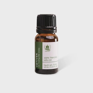 Peut inclure: Un petit flacon en verre ambré avec un bouchon à vis noir strié contenant de l'huile essentielle. L'étiquette blanche présente des accents verts et du texte incluant VETIVER, 100% TINH DẦU HỮU CƠ, et 10 ml / 0.33 fl oz, indiquant le volume du liquide.