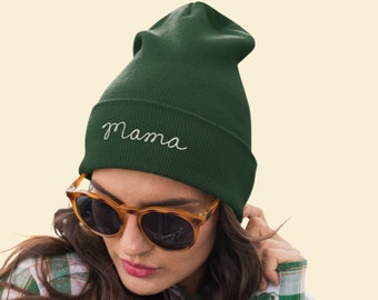 May include: A dark green beanie hat with the word "mama" embroidered in white script. The hat is made of a soft, knitted material. A fashionable accessory for everyday wear.