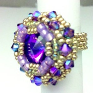 May include: A purple and gold beaded ring with a large, faceted purple gemstone in the center.