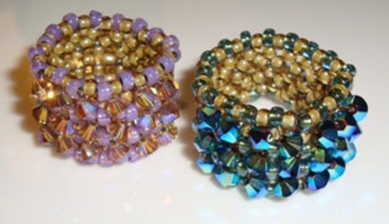 May include: Two beaded rings, one with purple and gold beads and the other with green and gold beads.