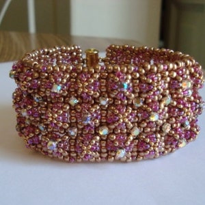 May include: A pink and gold beaded bracelet with iridescent crystals. The bracelet is made with small beads and has a delicate, intricate design.