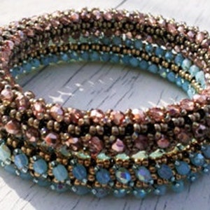 May include: A multi-colored beaded bracelet with a spiral design. The bracelet is made with light blue, teal, gold, and pink beads.